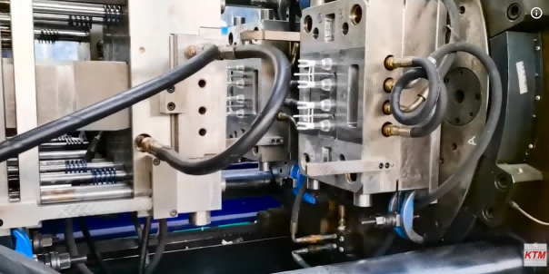 Technician operating two-shot injection molding machine at KTM factory